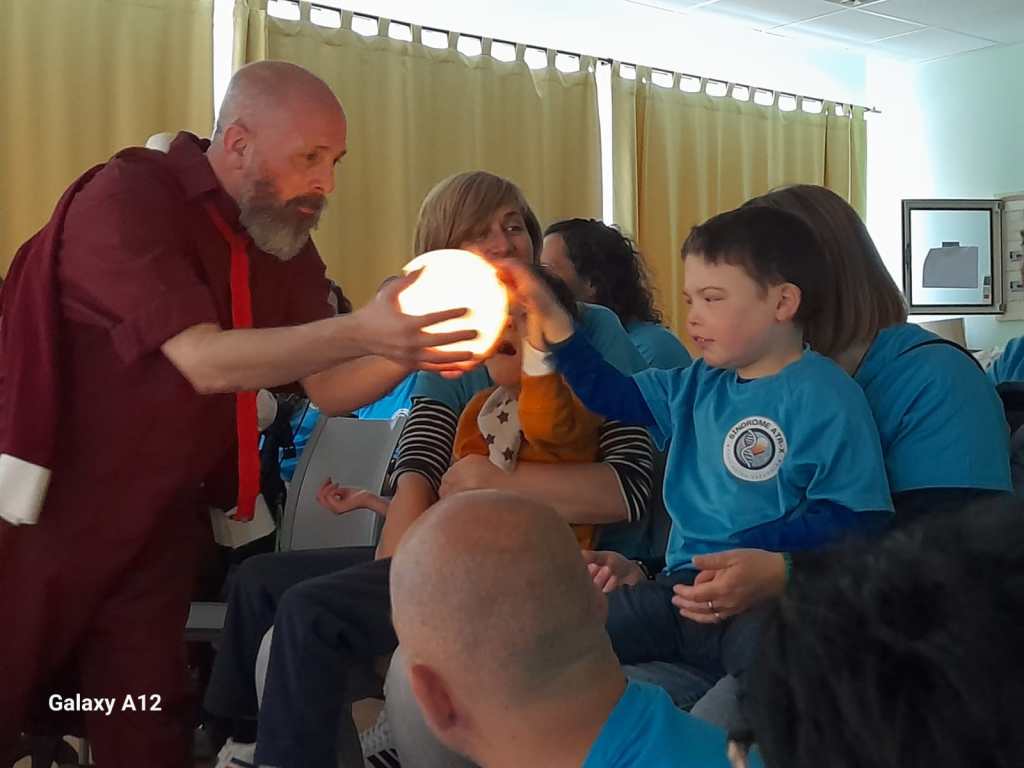 David, el actor, muetra una bola iluminada que los niños miran y tocan fascinados